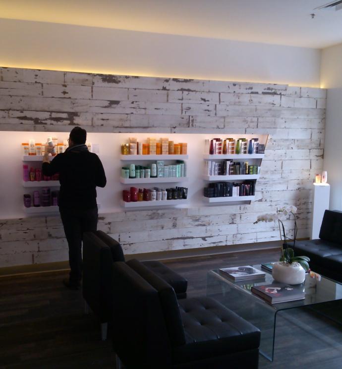 The reclaimed material works throughout all of the different areas of the salon. Here it surrounds the retail product display.