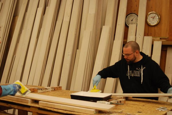 Dave works on the application of the white finish. Behind him you can see a clock and thermometer. Temperature can be a crucial factor in finish application and successful curing so it’s closely monitored.