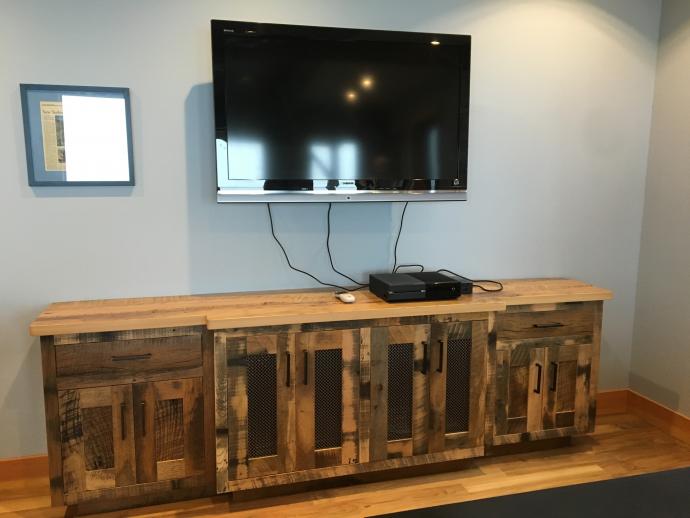 The lower level rec room includes an entertainment center crafted with Reclaimed Settlers’ Plank Hardwoods and topped with Reclaimed American Gothic hardwoods (crafted by NEWwoodworks).