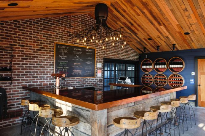 Tasting room with Pioneer Millworks reclaimed wood Center-cut Vat Stock (this batch is oak) on the ceiling and reclaimed timber skins on the bar front. Photo by Matt Wittmeyer.