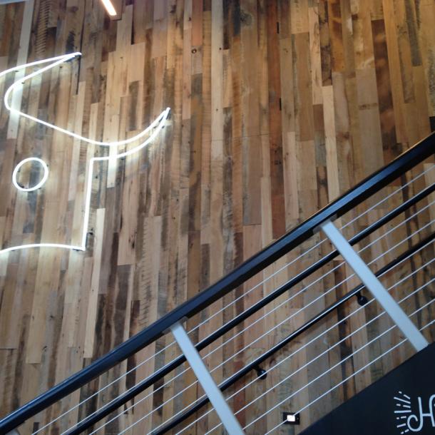 Close up of the Settlers' Plank Mixed Hardwoods wall paneling with the Dos Toros bull logo lit up.