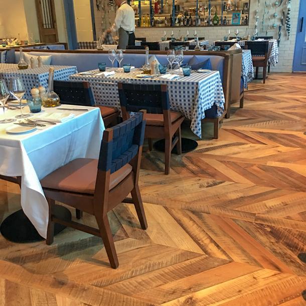Pioneer Millworks reclaimed Settlers' Plank Mixed Hardwoods in Dolce Riviera restaurant in Dallas, Texas. Installed in a chevron pattern.