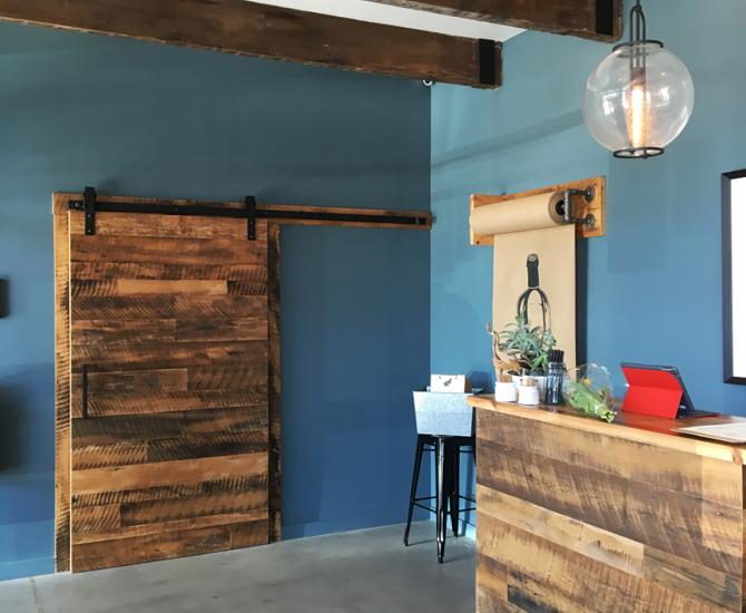 A flat track door and hostess station were made with Settlers' Plank reclaimed hardwoods by NEWwoodworks.