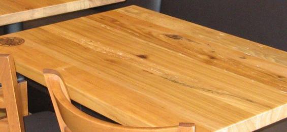 Pizzeria patrons can enjoy slices on a mixture of reclaimed hardwood table tops.