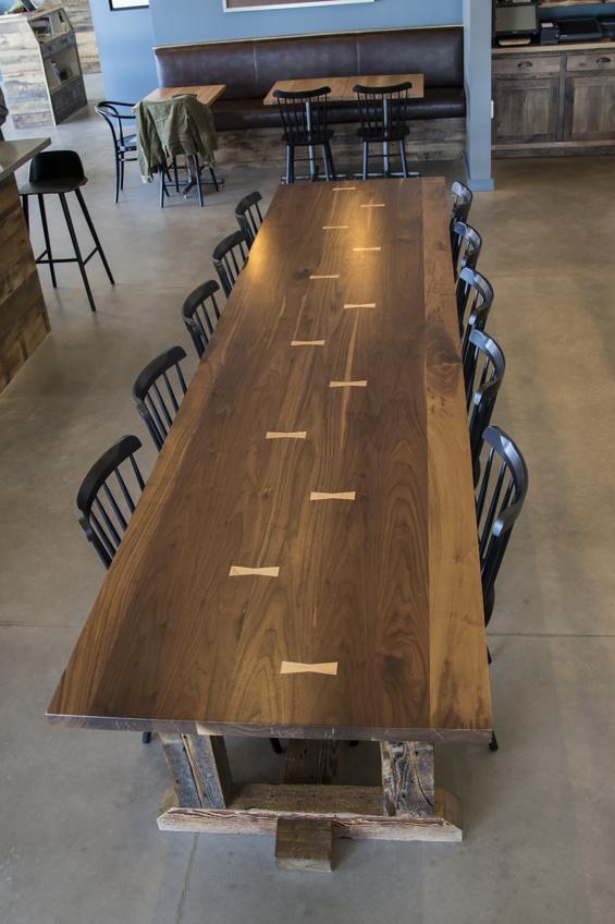 A walnut community table with reclaimed hemlock base crafted by NEWwoodworks seats 12.