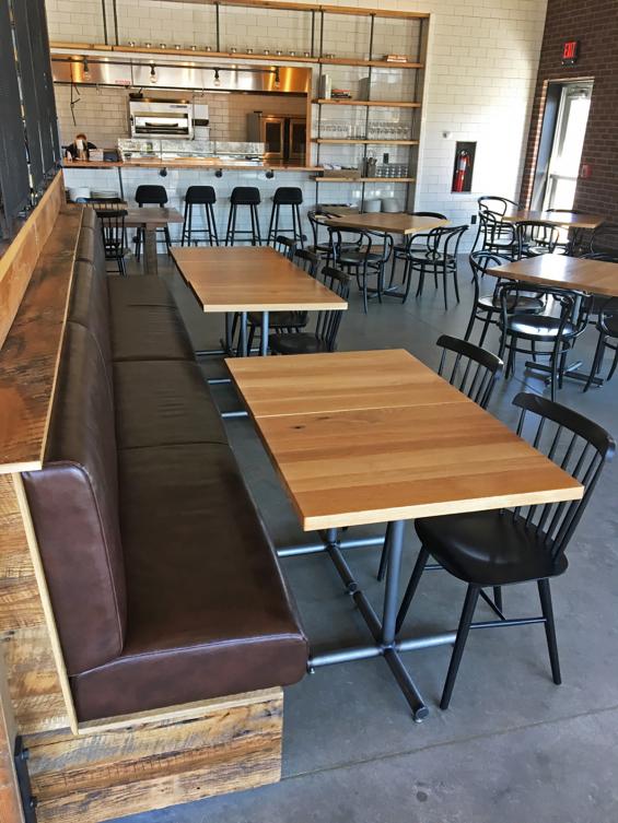Reclaimed Settlers' Plank Mixed Hardwoods clad a long bench while square top Oak tables allow flexible seating behind the bar area at Kindred Fare. All crafted by NEWwoodworks.