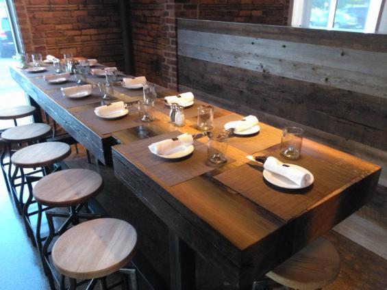 Reclaimed from a canal lock, tha massive reclaimed Douglas fir timber was sawn into slabs to from community tables at TRATA in Rochester, NY.