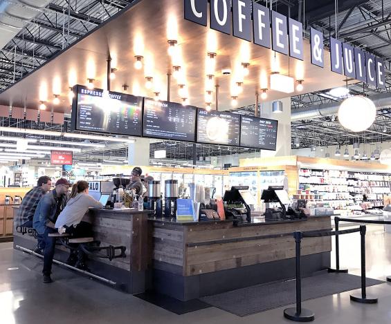 Pioneer Millworks Settlers Plank mixed oak reclaimed wood paneling wraps around the coffee bar inside Whole Foods Buffalo.