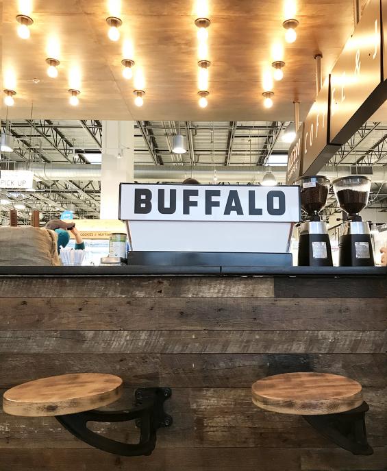 Pioneer Millworks Settlers Plank mixed oak reclaimed wood paneling wraps around the coffee bar inside Whole Foods Buffalo.