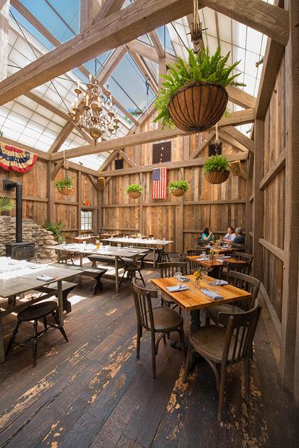 Inside the timber frame "barn" dining room, crafted by New Energy Works, more American Prairie Brown Board clads the walls adjacent to an electronic skylight. Flooring here is a one-off from reclaimed thresher boards. 