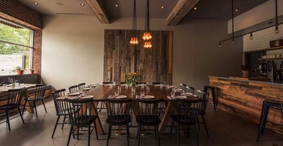 Reclaimed weathered wall paneling and custom tables form the centerpieces of this special occasion dining room in this farm-to-table eatery.