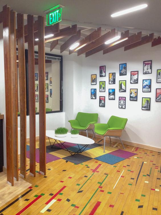 Pioneer Millworks reclaimed gym flooring in a confetti pattern and reclaimed bleacher boards used on a vertical and ceiling.